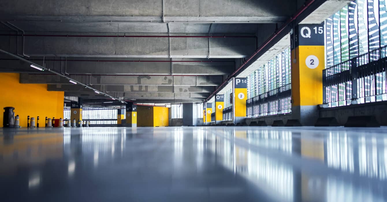 Empty garage with parking lots with concrete ceiling and flooring and pillars marked with numbers.