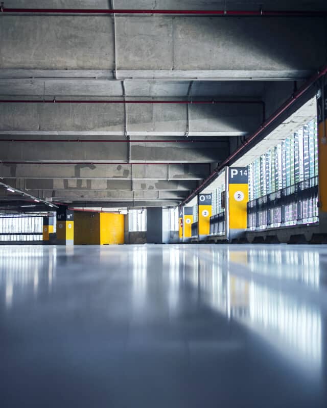 Empty garage with parking lots with concrete ceiling and flooring and pillars marked with numbers.